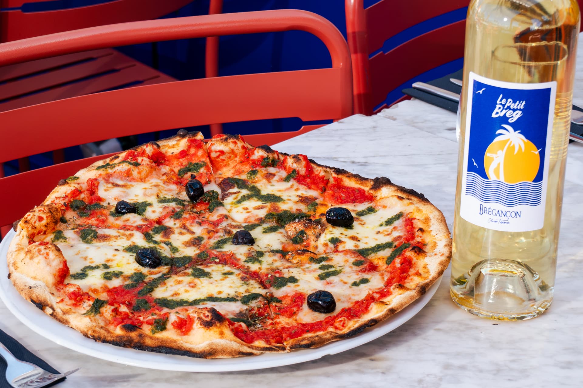 Pizza mozzarella basilic au feu de bois servie en terrasse